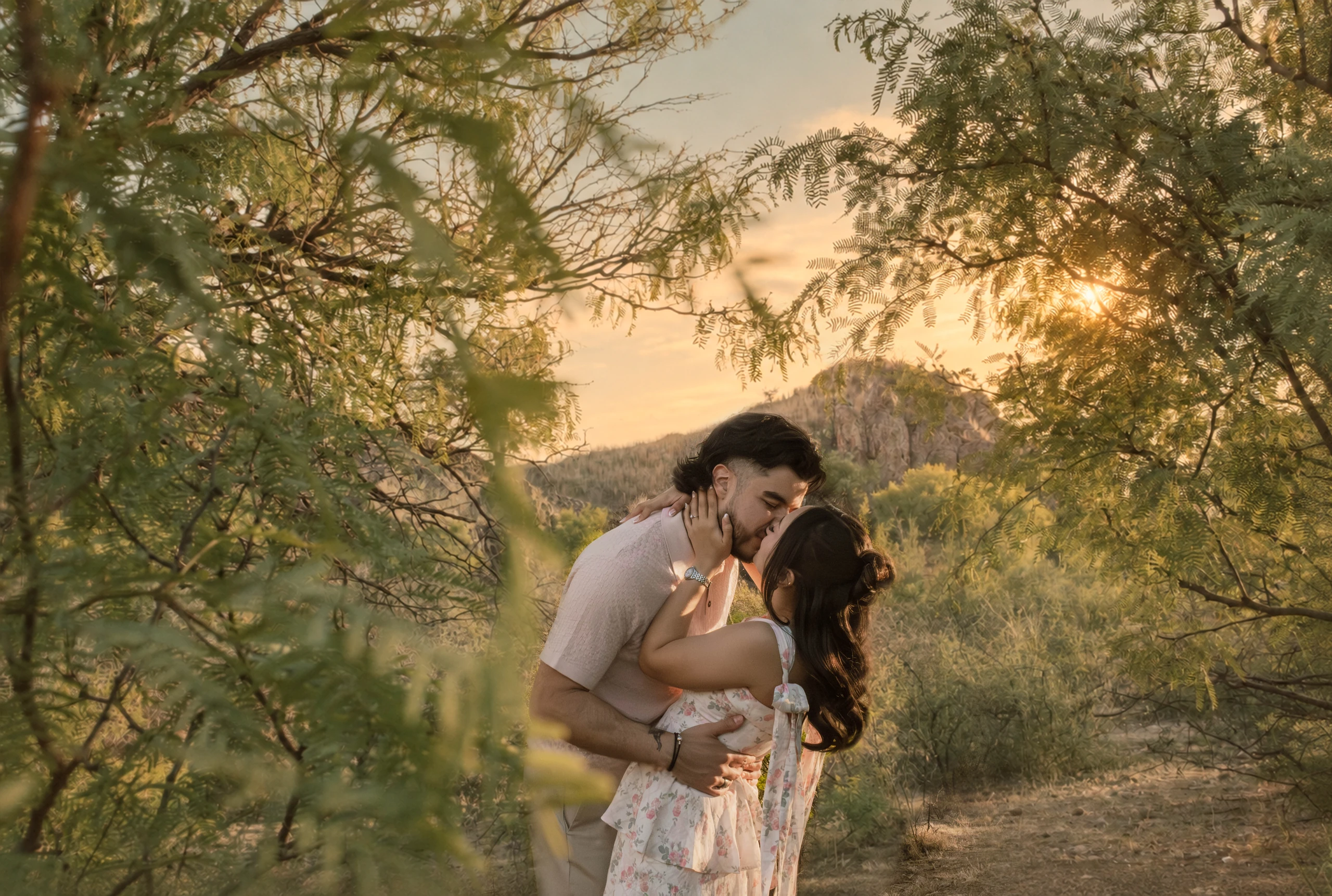 Natalia y Gonzalo besándose entre árboles al atardecer